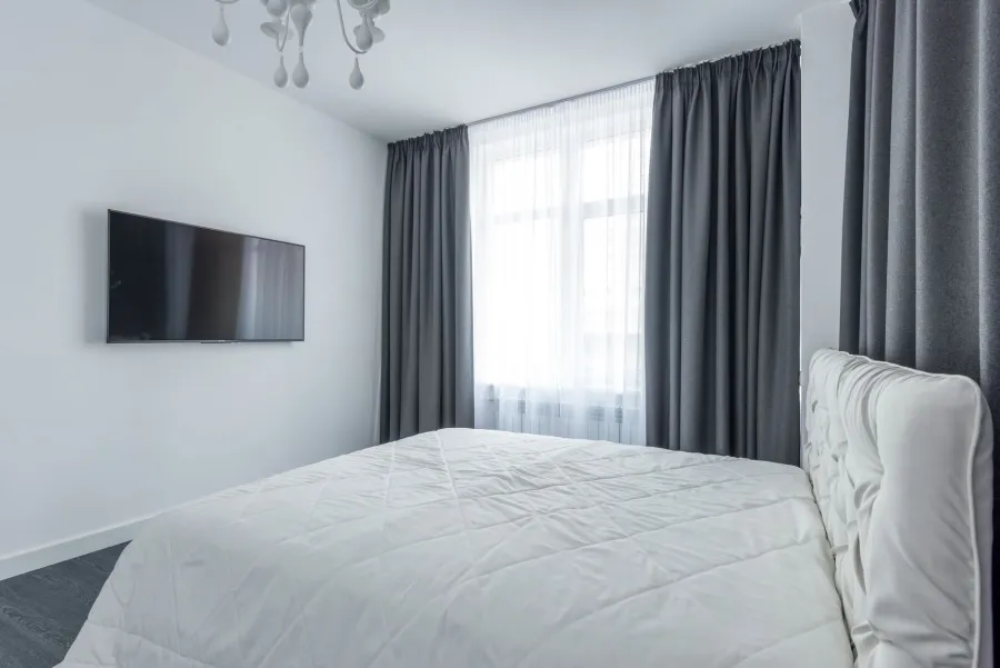 Grey curtains layered with white sheers in a bedroom