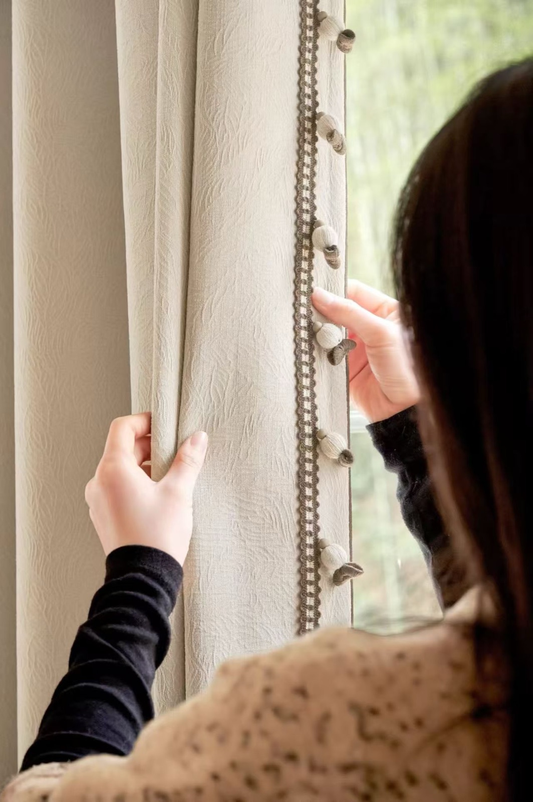 Person adjusting a made-to-measure curtain by the window